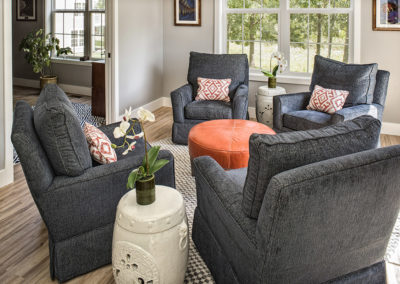 Living room with four navy comfortable chairs with orange ottoman