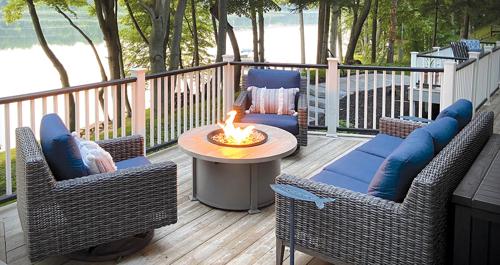 Deck with patio furniture and a lit fire table.